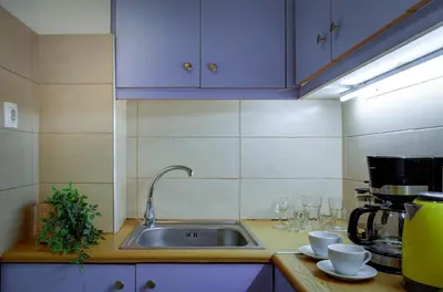 a kitchen with a sink and wine glasses on a counter at Sunny all day apartment near Athens city center in Athens