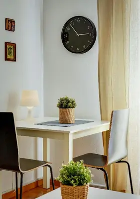 a table with two chairs and a clock on a wall at Sunny all day apartment near Athens city center in Athens