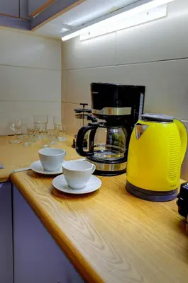 a counter with a yellow coffee maker and cups on it at Sunny all day apartment near Athens city center in Athens