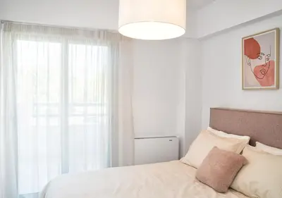 a white bedroom with a bed and a window at Sia Mare in Kalívia Thorikoú