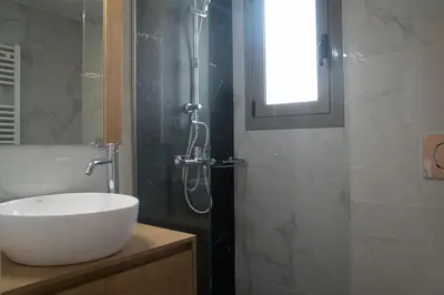 a bathroom with a white sink and a shower at Sia Mare in Kalívia Thorikoú