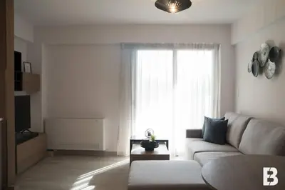 a living room with a white couch and a window at Sia Mare in Kalívia Thorikoú
