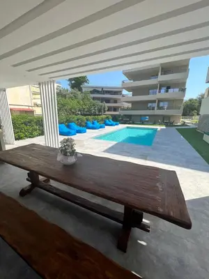 a wooden table in front of a swimming pool at Sia Mare in Kalívia Thorikoú