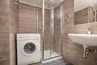 a bathroom with a washing machine and a sink at Modern Hospitality- apt near Children's Hospital in Athens