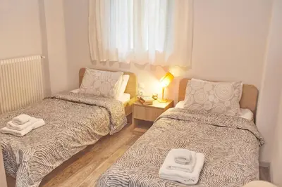 a small room with two beds and a chair at Modern Hospitality- apt near Children's Hospital in Athens