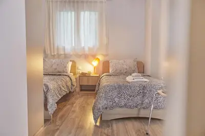 a small bedroom with two beds and a window at Modern Hospitality- apt near Children's Hospital in Athens
