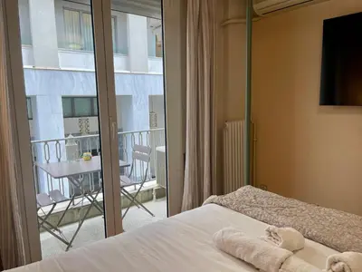 a bedroom with a bed and a balcony with a table at Athens Spirit Apartment in Athens
