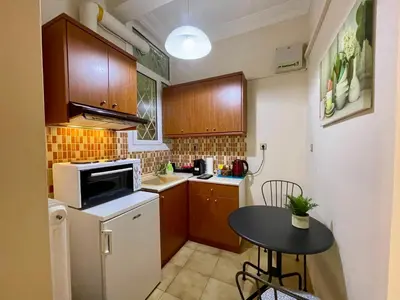 a small kitchen with wooden cabinets and a small table at Athens Spirit Apartment in Athens