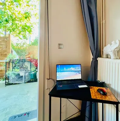 a laptop computer sitting on a table next to a window at Cozy Studio in Athens Riviera, next to SNFCC in Athens