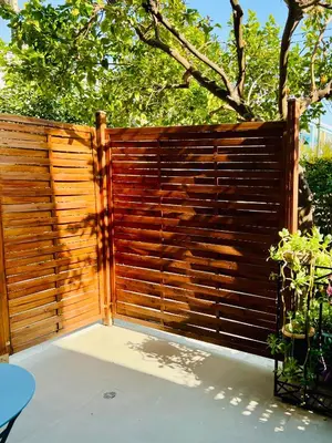 a wooden privacy fence with a tree in the background at Cozy Studio in Athens Riviera, next to SNFCC in Athens