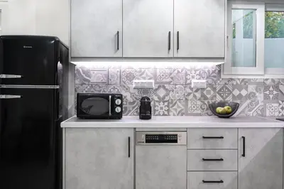 a kitchen with a black refrigerator and white cabinets at apt Eleven - cozy apartment with garden in Athens