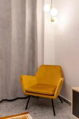 a yellow chair in a room with a curtain at Elegant Apt 5' from Ampelokipi Metro Station in Athens
