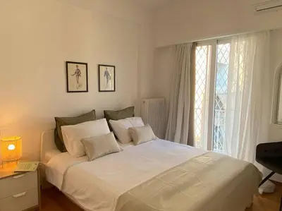 a white bed in a bedroom with a window at Kolonaki Oasis in Athens