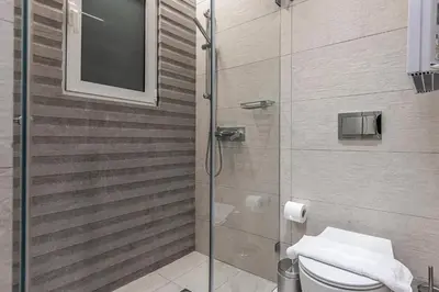 a bathroom with a shower with a toilet and a television at Phaedrus Living City Center Lux Flat Kolonaki in Athens