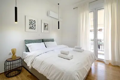 a white bedroom with a large bed with towels on it at Spacious 3-Bedroom Retreat in the Heart of Pagrati in Athens