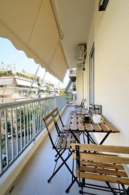 a balcony with wooden tables and chairs on a building at Spacious 3-Bedroom Retreat in the Heart of Pagrati in Athens