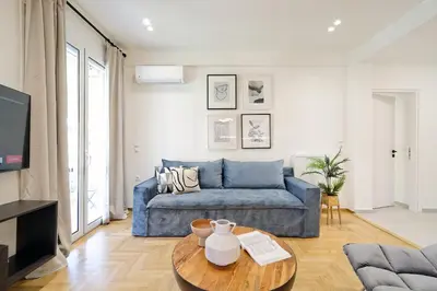 a living room with a blue couch and a table at Spacious 3-Bedroom Retreat in the Heart of Pagrati in Athens