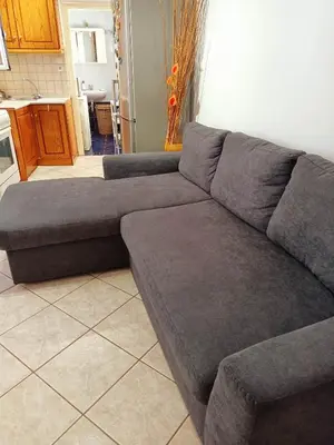 a gray couch in a room with a kitchen at Detached house with a lovely yard 5' walk from Metro Station Agios Dimitrios and METRO MALL in Athens