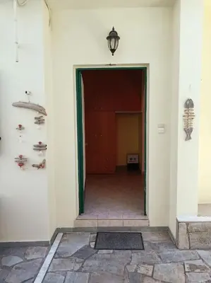 a hallway with a door to a room with shoes on the wall at Detached house with a lovely yard 5' walk from Metro Station Agios Dimitrios and METRO MALL in Athens