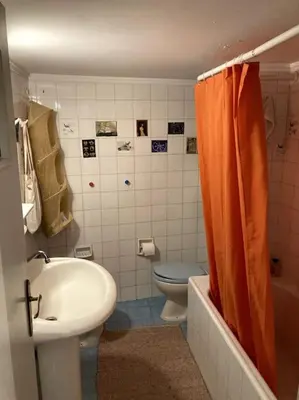 a bathroom with an orange shower curtain and a toilet at Sunny calm apartment in pedestrian street in Athens