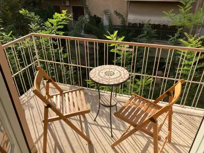 two chairs and a table on a balcony at Sunny calm apartment in pedestrian street in Athens