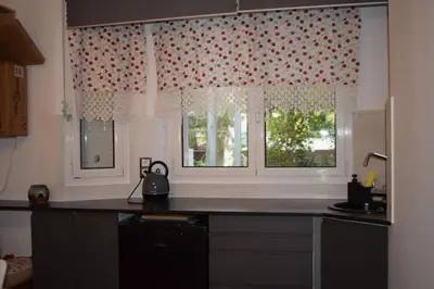a kitchen with a counter and two windows with curtains at h2h Chris # Μικρό, φωτεινό & βολικό σπίτι in Athens