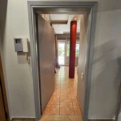 a hallway with a door leading into a room with a red pole at Diocharous garden apartment in Athens