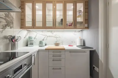 a kitchen with white counters and wooden cabinets at Charming apartment in Kolonaki, Peridot - Homes in Athens