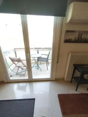a room with a balcony with a table and a glass door at SAILORS LUXURY APPARTMENT 130m2 in Athens