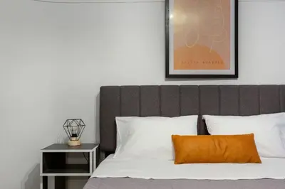 a bed with a brown headboard and an orange pillow at Central apartment in the heart of Historic Center in Athens