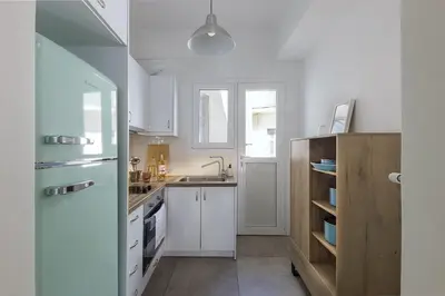 a kitchen with white cabinets and a sink at Lovely 1-bedroom apt with balcony in Athens