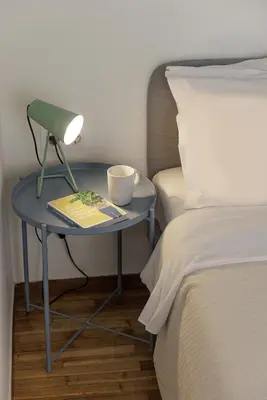 a table with a lamp and a book on it next to a bed at Lovely 1-bedroom apt with balcony in Athens