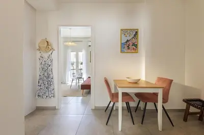 a dining room with a table and chairs and a dress hanging on the wall at Lovely 1-bedroom apt with balcony in Athens