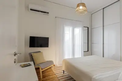 a bedroom with a bed and a chair and a tv at Lovely 1-bedroom apt with balcony in Athens