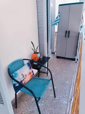 a green chair with a table and a refrigerator at Sweet home in Athens in Athens