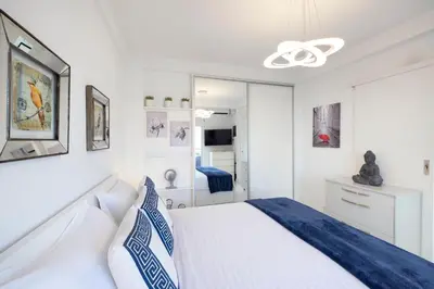 a white bedroom with a bed and a ceiling fan at Acropolis Views Studio in Athens
