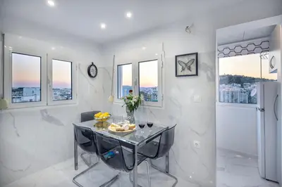 a dining room with a table and chairs and windows at Acropolis Views Studio in Athens