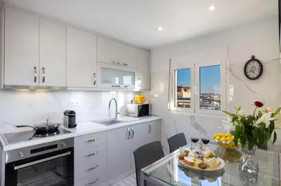 a kitchen with white cabinets and a glass table at Acropolis Views Studio in Athens