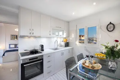 a kitchen with white cabinets and a glass table at Acropolis Views Studio in Athens