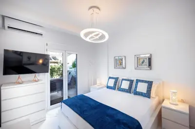 a white bedroom with a bed and a tv at Acropolis Views Studio in Athens