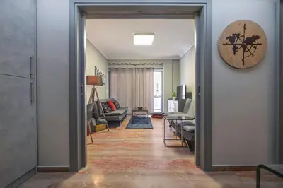 a living room with a couch and a clock on the wall at Beautiful apt in Glyfada Center, Papandreou Street in Athens