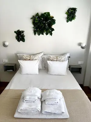 a bed with two towels and two plants on the wall at Sky Apt Unique, Spotless, 2BR, 2BA, Stunning View in Athens