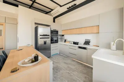 a kitchen with white cabinets and a wooden table at Sky Apt Unique, Spotless, 2BR, 2BA, Stunning View in Athens