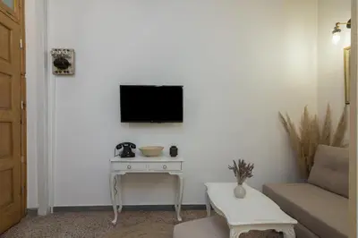 a living room with a table and a tv on a wall at Stoa Kairi Loft A in Athens