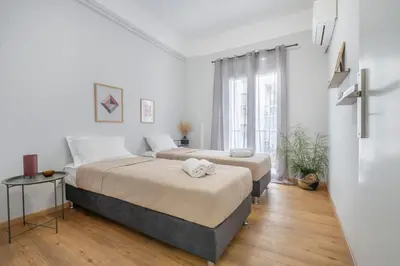 two beds in a room with white walls and wooden floors at Luxury 2 bdroom apt- Megaro Mousikis in Athens