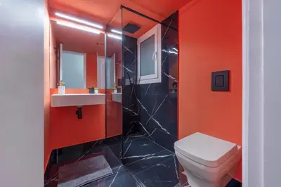 a bathroom with a toilet and a sink and orange walls at Luxury 2 bdroom apt- Megaro Mousikis in Athens
