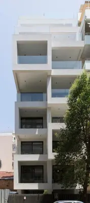 a white building with a tree in front of it at Cubes Living Athens Goudi in Athens
