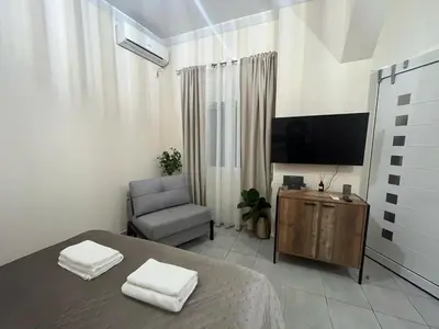 a bedroom with a bed and a tv and a chair at Golden Fleece Apartment VIPGreece in Athens