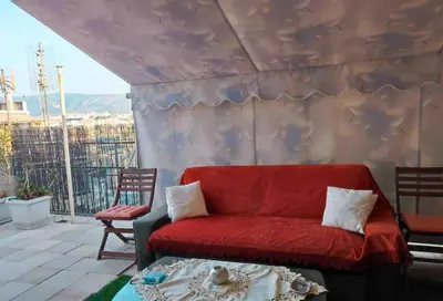 a red couch sitting on top of a balcony at Spacious private rooftop studio, mountain and sea view in Athens