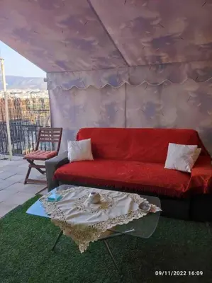 a living room with a red couch and a table at Spacious private rooftop studio, mountain and sea view in Athens
